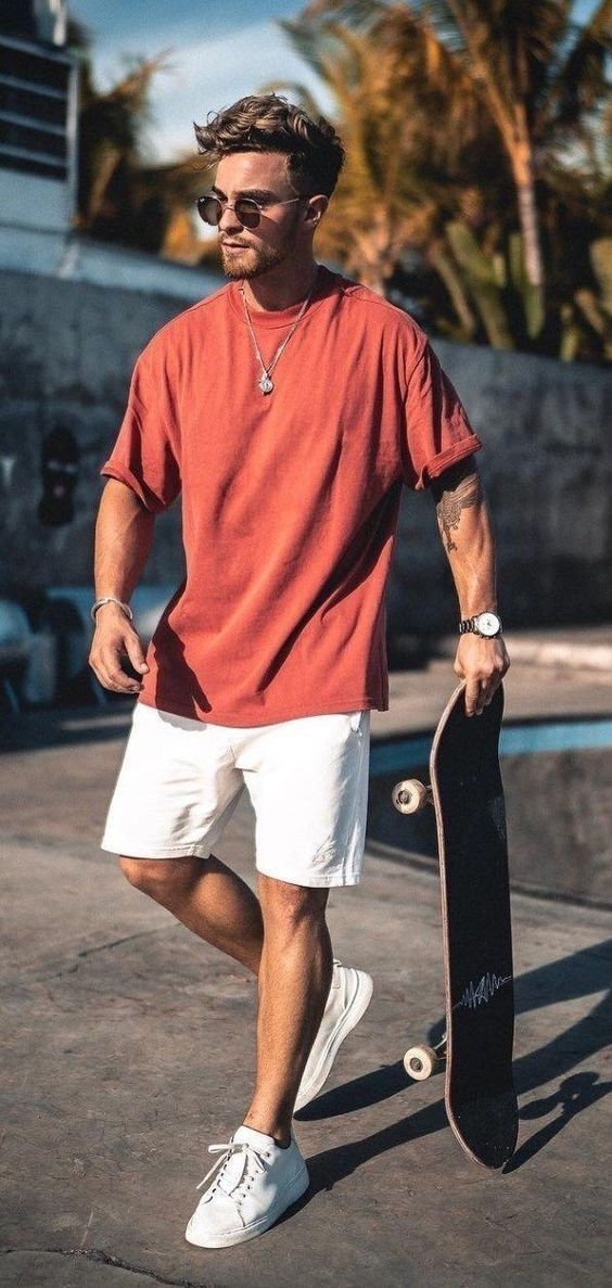 A portrait of man wearing sunglasses, coral T-shirt, and white shorts.