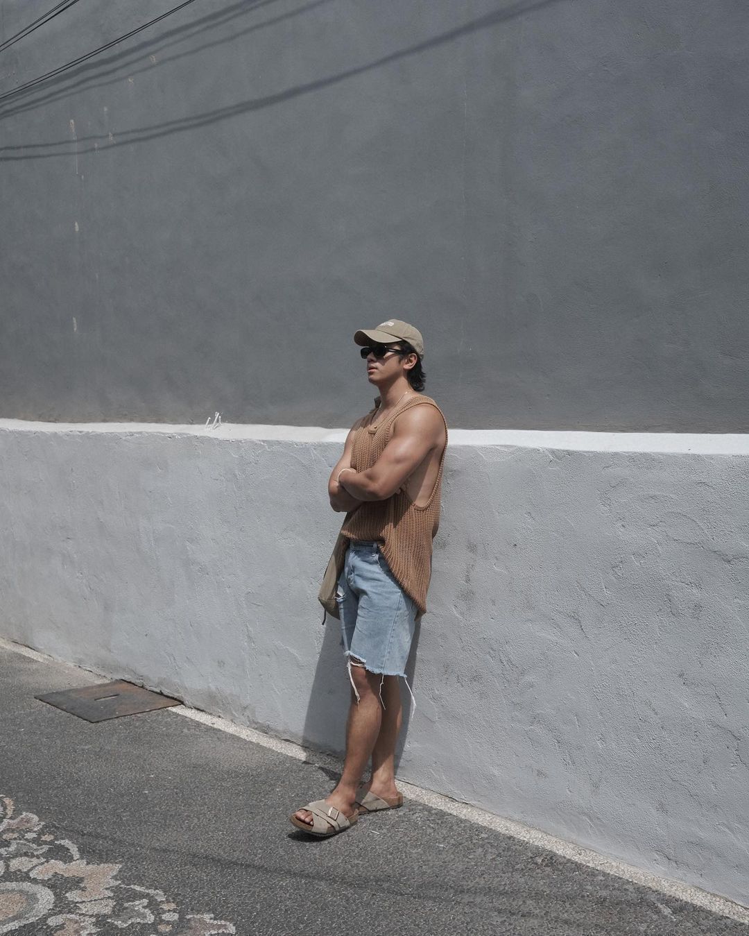 A portrait of man wearing tank top, shorts, and baseball cap.