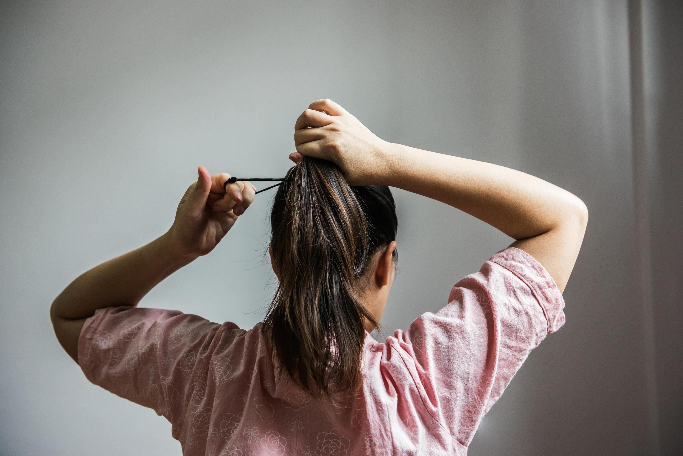 Woman collecting hair into a ponytail