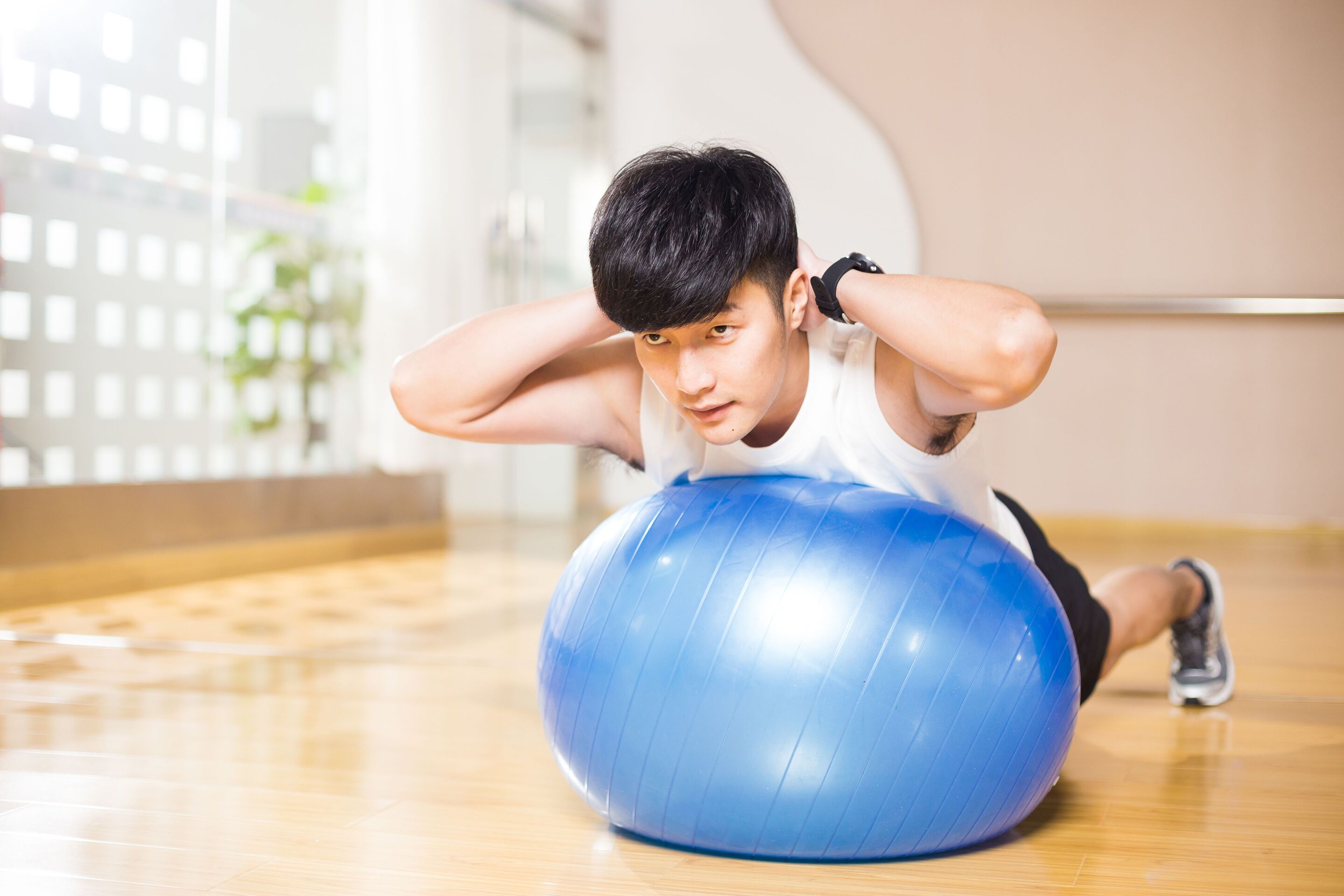 Young Asian man working out with an exercise ball