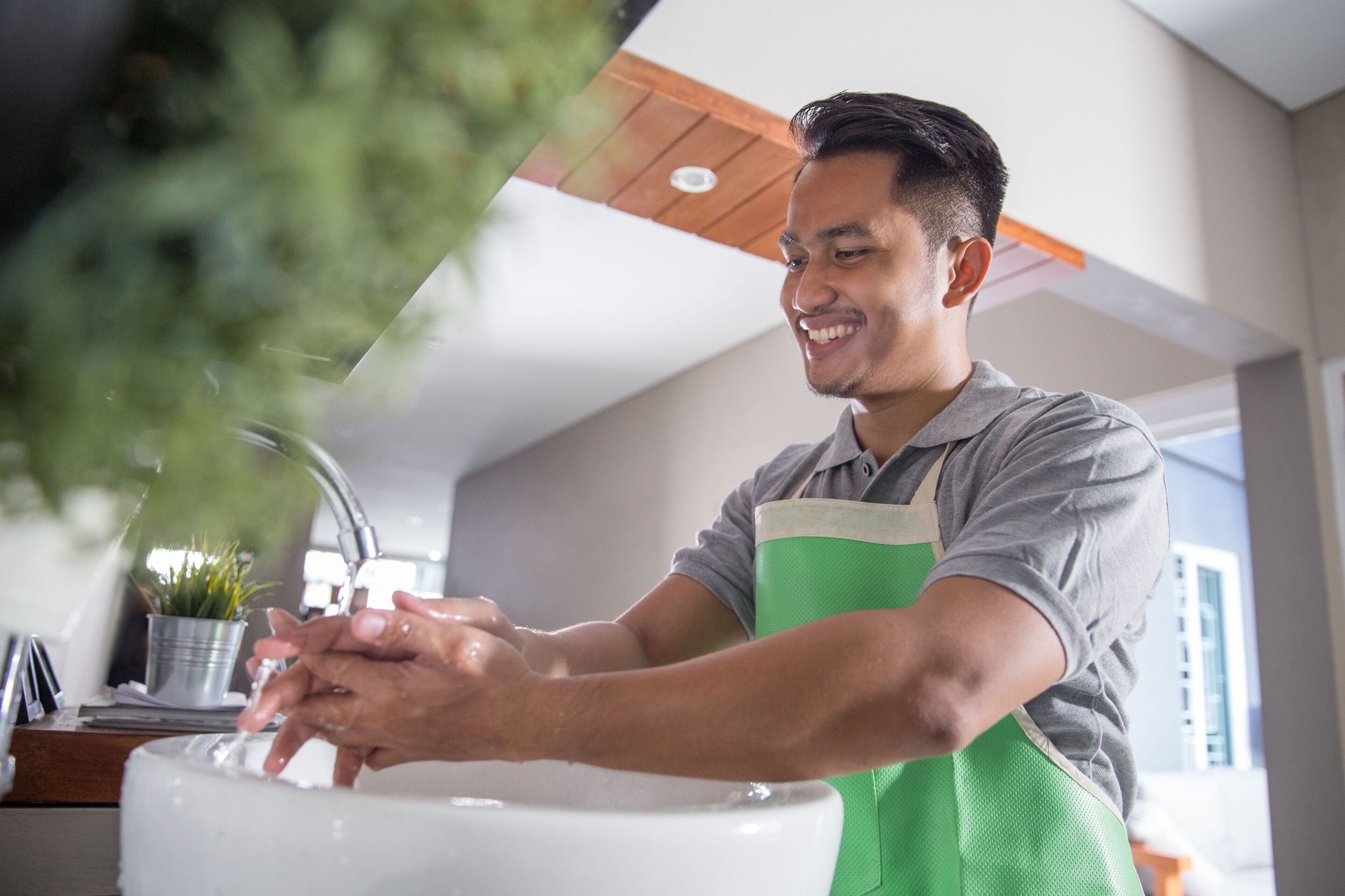 Smiling man washing hands in a sink