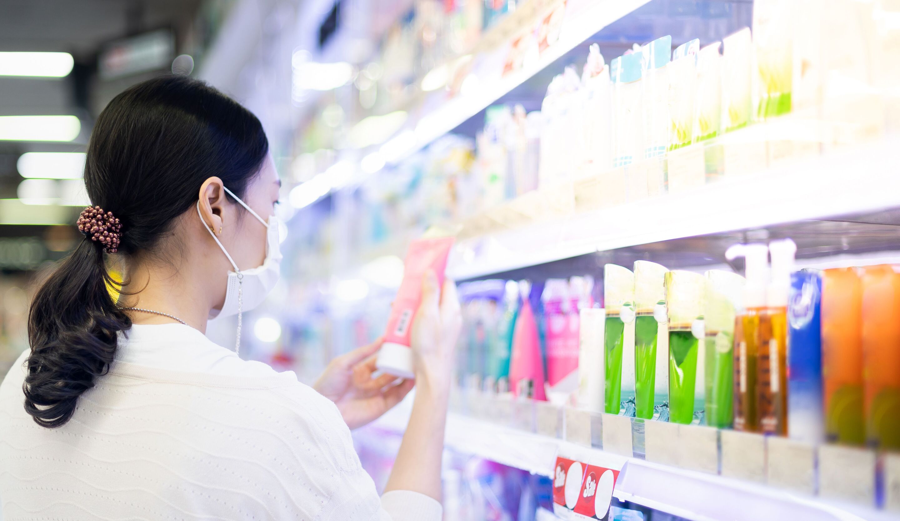 A woman looking at the ingredients of a bottle