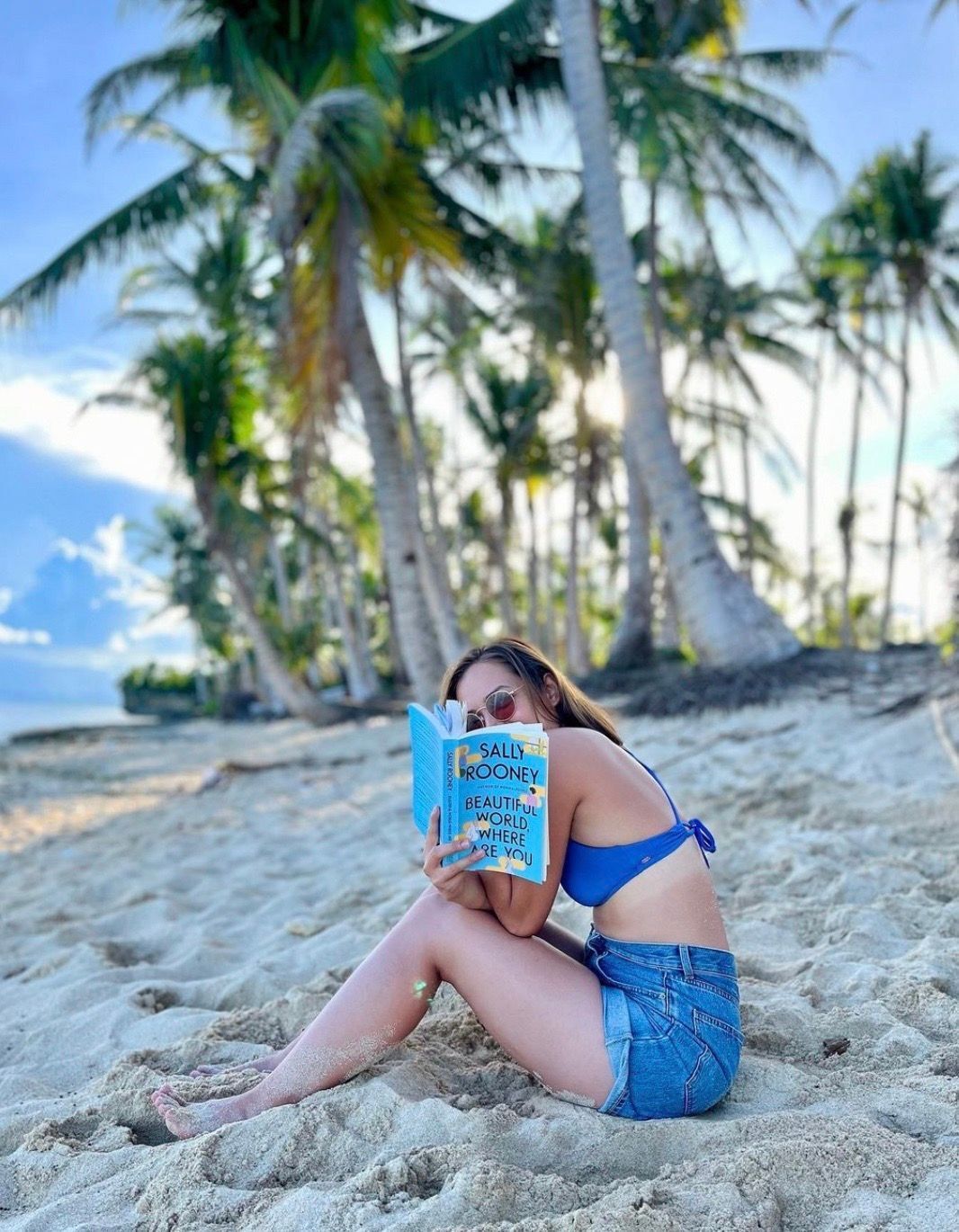 Asian woman reading by the beach.