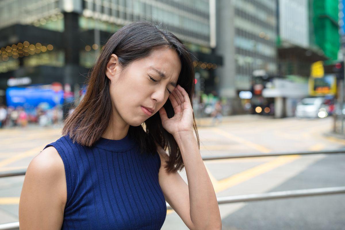 Asian woman with a headache touching her temples