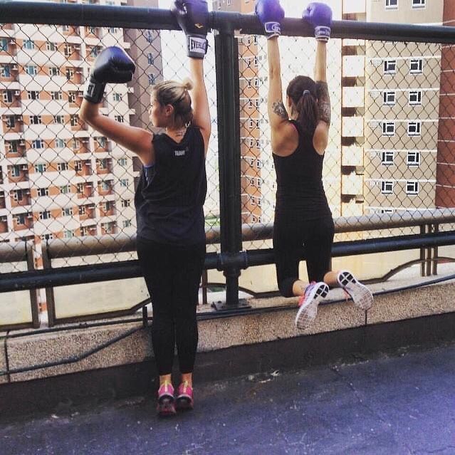 Two women looking out the rooftop, wearing sport attires and boxing gloves
