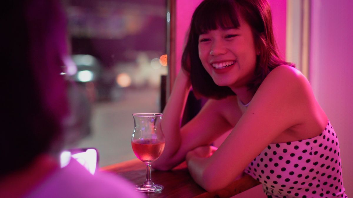 Young Asian woman having a drink at a bar