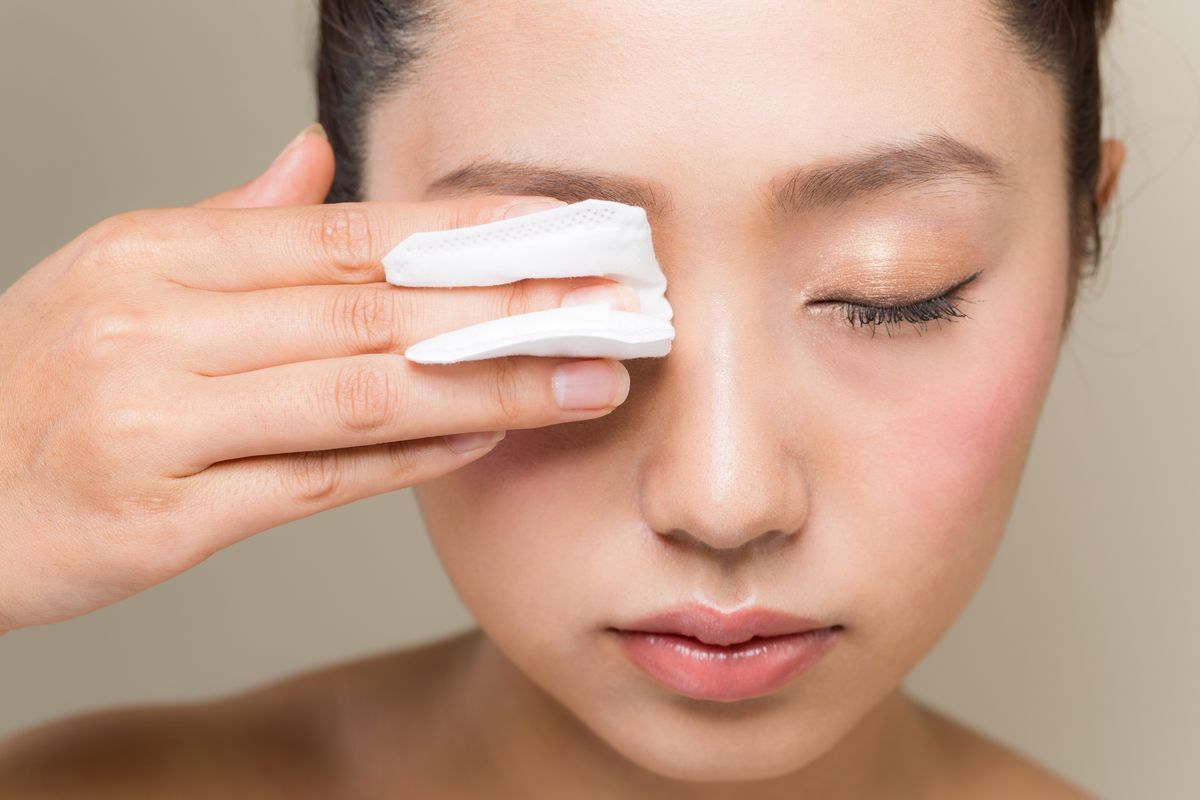 Woman removing her eye makeup with a cotton pad. 