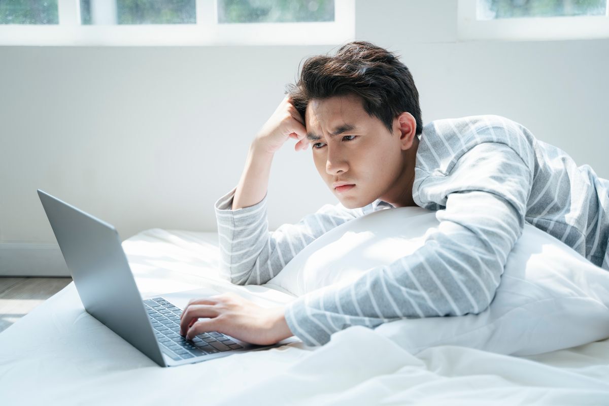 Man looking at his laptop screen with a confused expression.