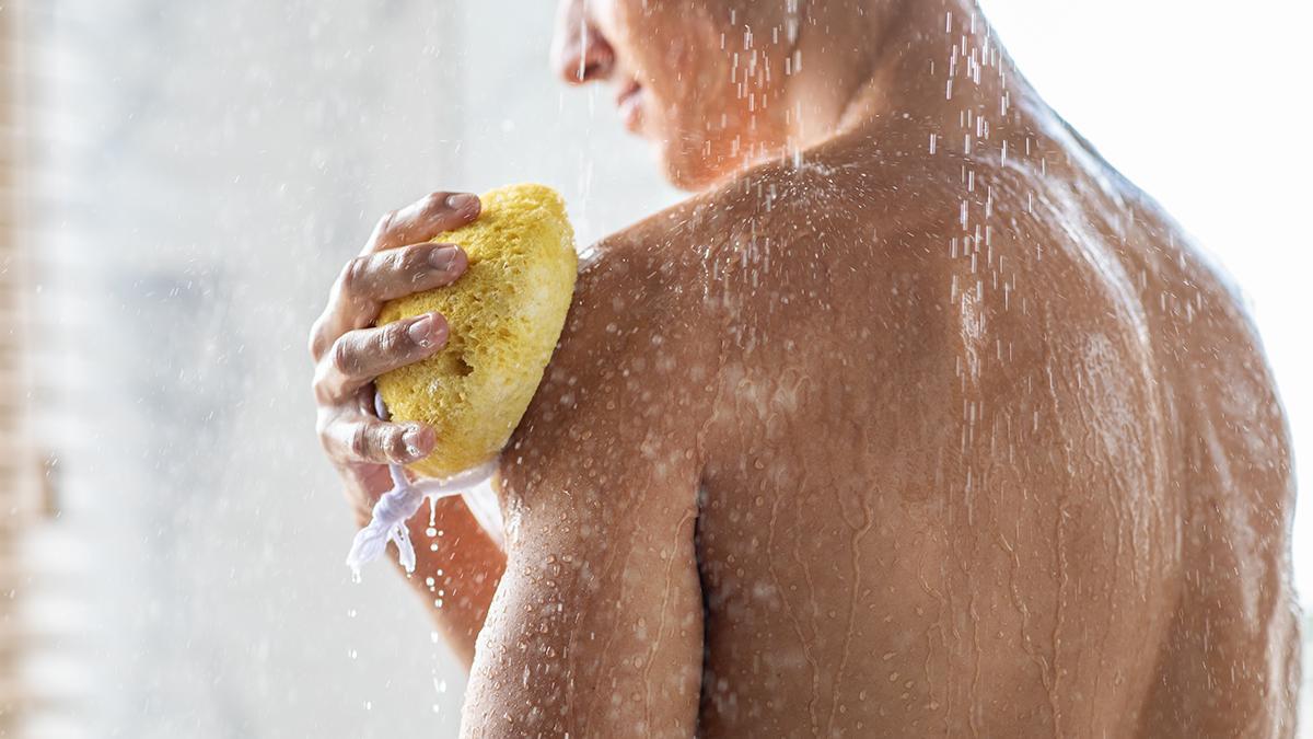 Man uses a bath sponge in the shower.