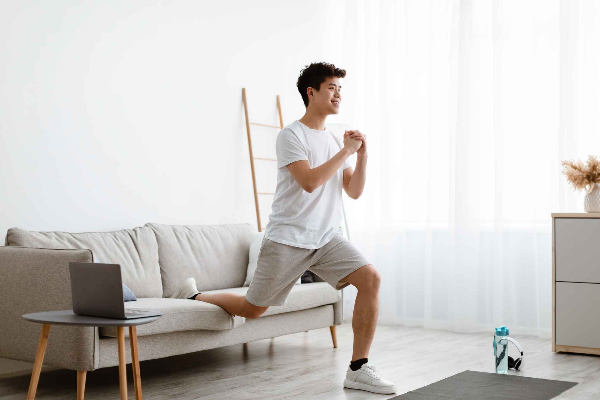 A man doing split squats at home with his couch for support.