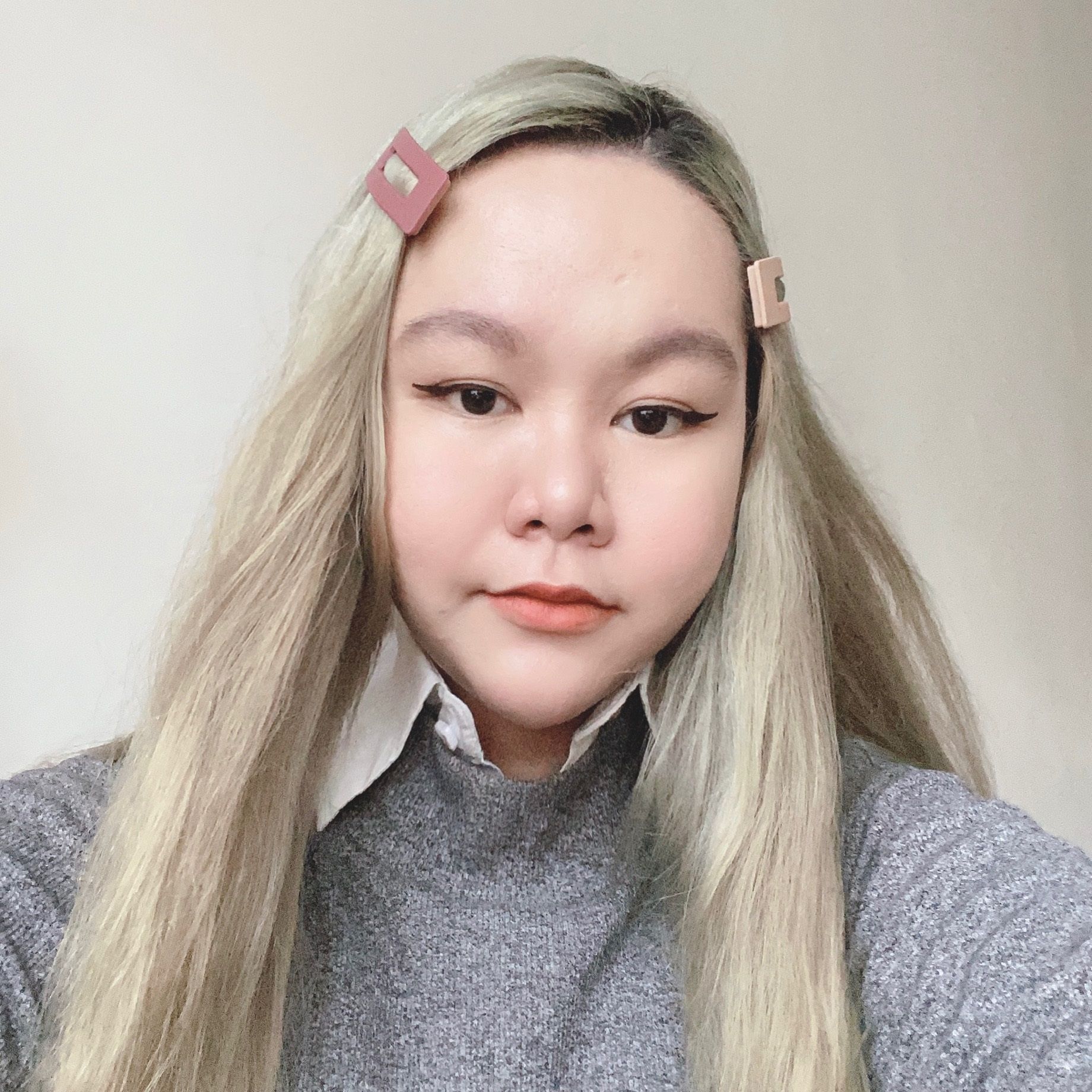 Woman with blonde hair wearing gray sweater. 