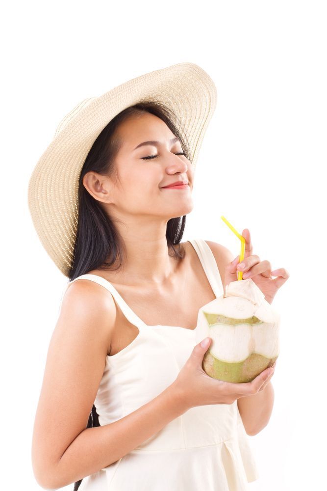A woman drinking from a coconut