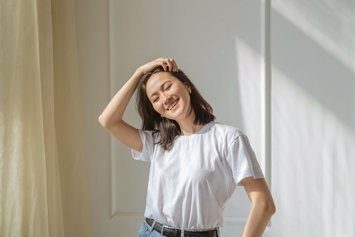 Woman in white t shirt running her hair through her fingers.  