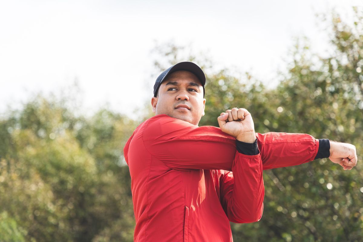 Asian man in red jacket stretching arms 