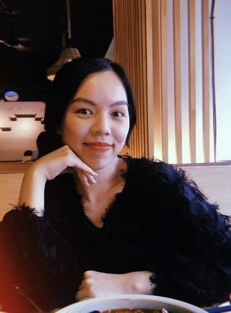 Asian woman leaning her head on her hand and smiling. 