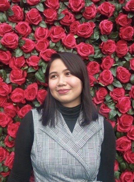 Asian woman smiling against a background of roses.