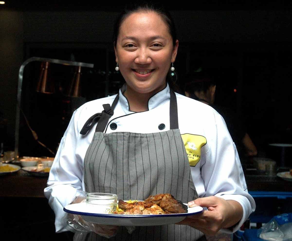 A female chef holding a plate of her signature dish 