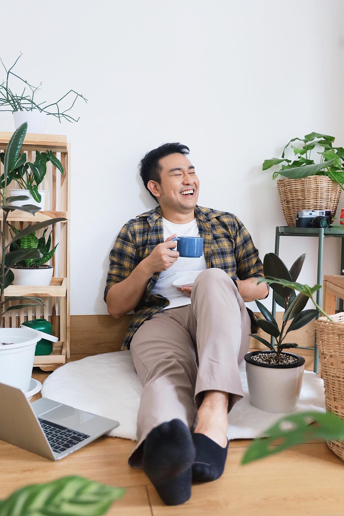 Asian man drinking coffee surrounded by plants