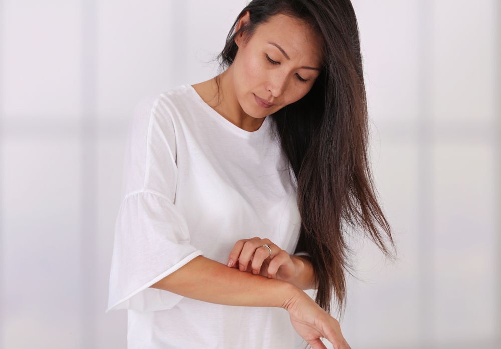 A woman scratching her arms.