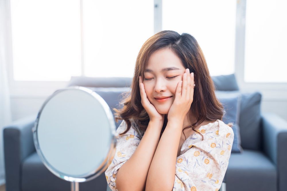 An Asian woman touching her face.