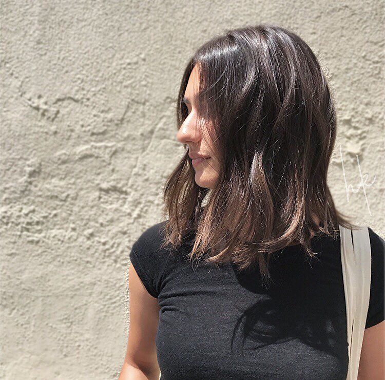 Woman with choppy lob wearing black shirt and white tote bag. 