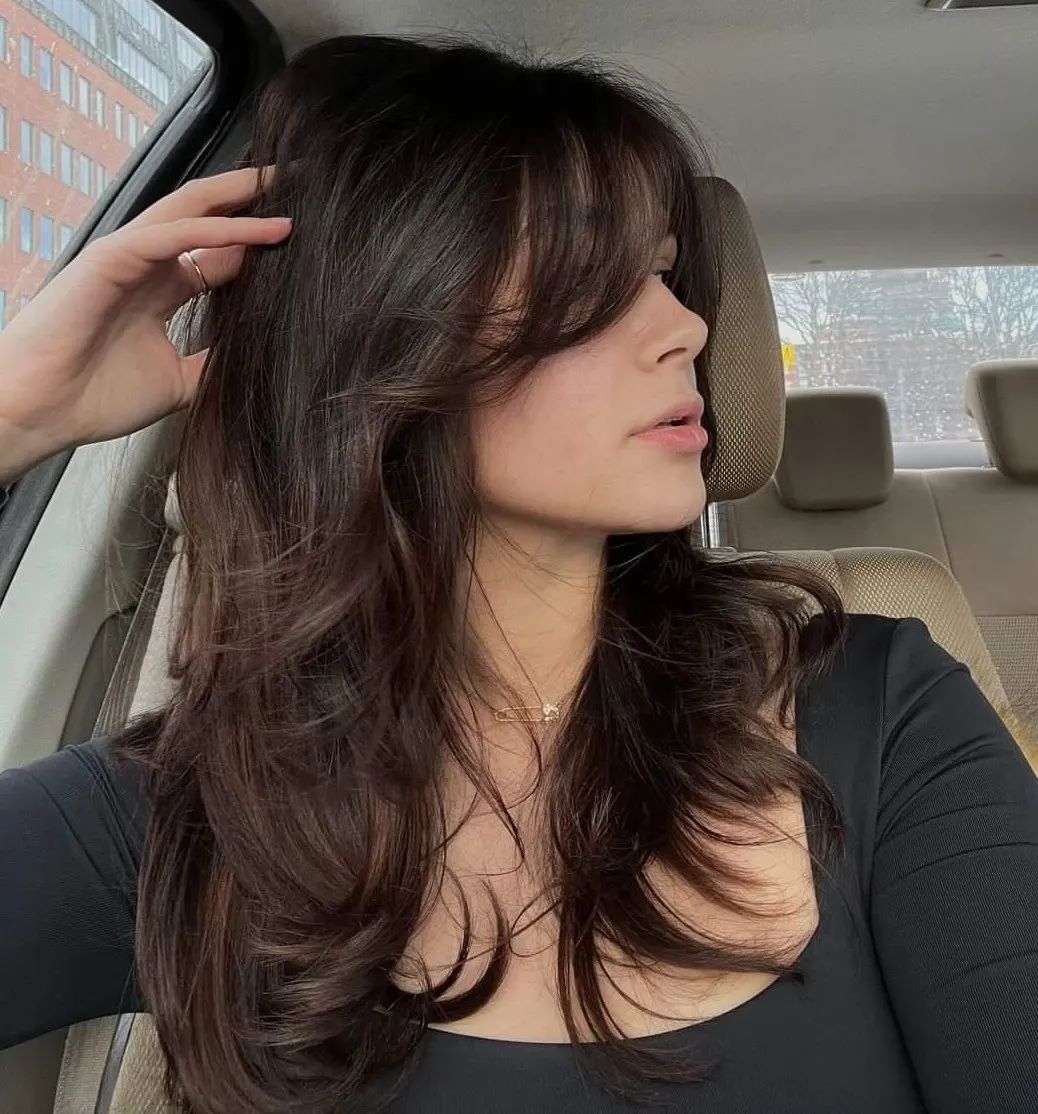 Woman with brown butterfly haircut wearing black top.