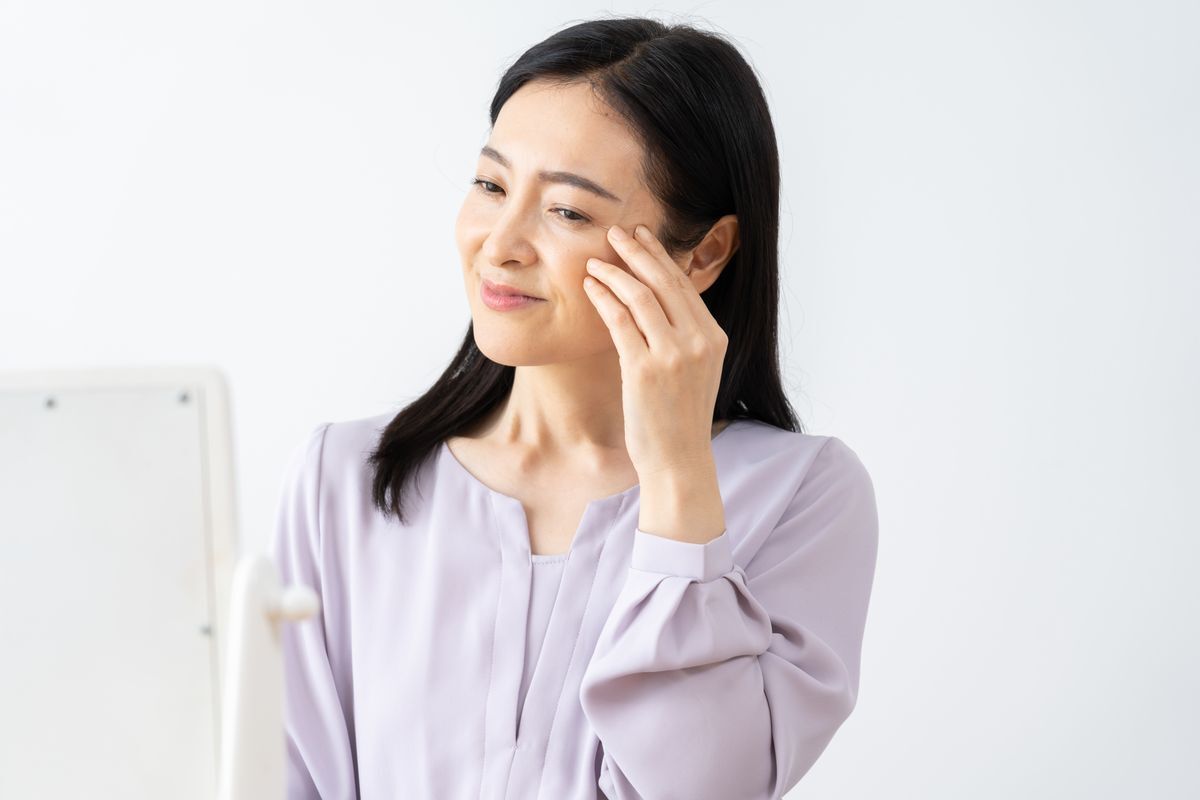 A middle aged woman massaging her eye with her fingers.
