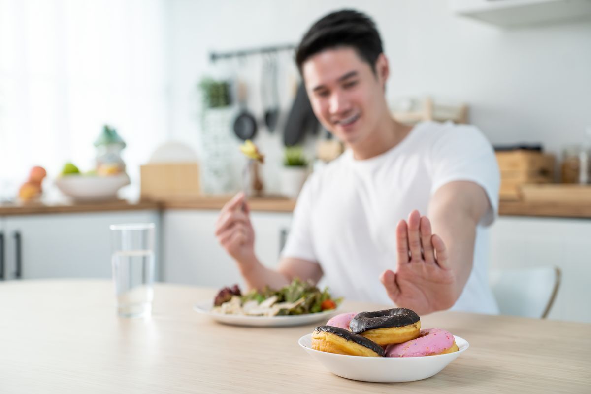 Asian man signaling no to donuts.