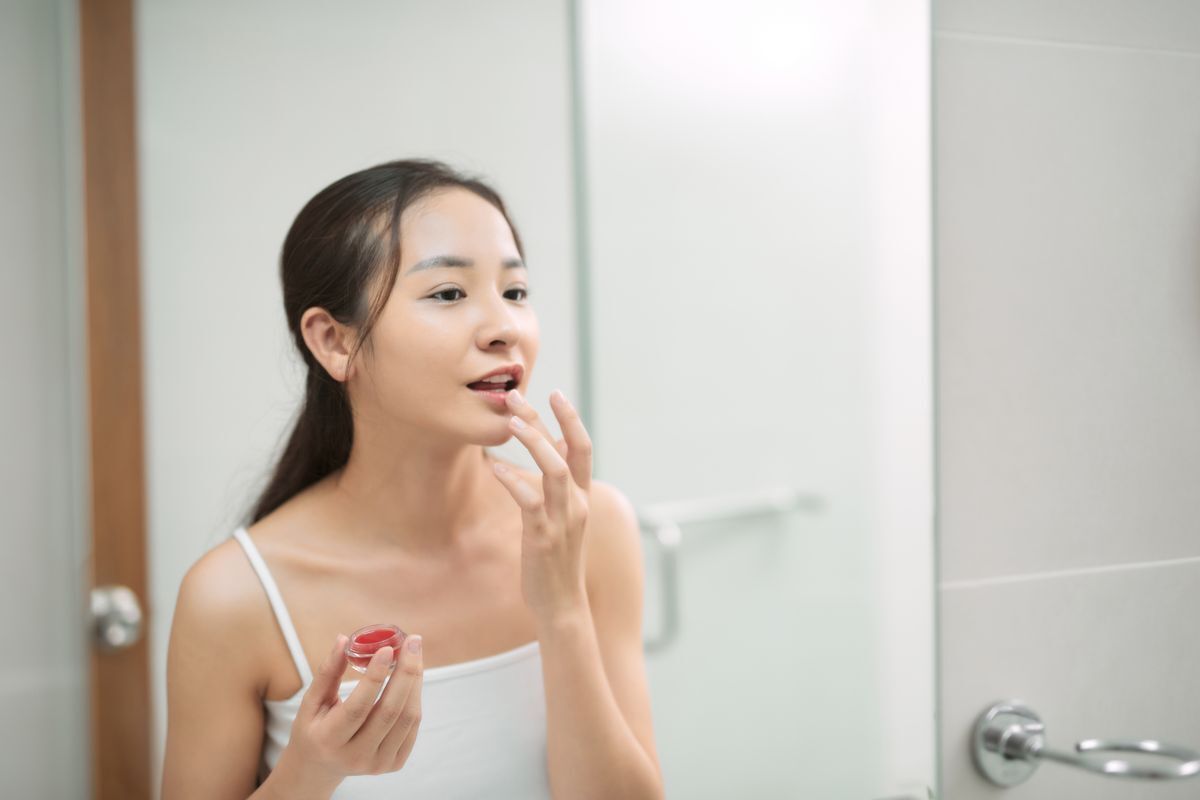 Asian woman using a lip scrub.