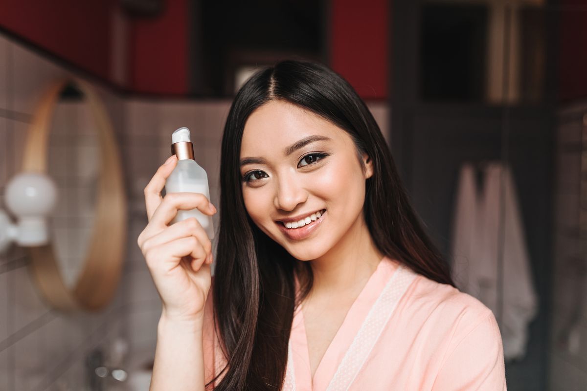 Filipino woman holding facial serum to her face