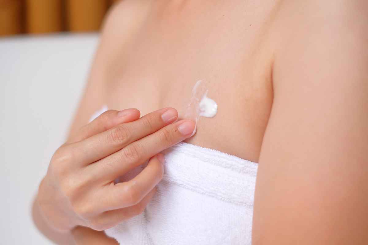 Woman putting ointment on her chest acne.