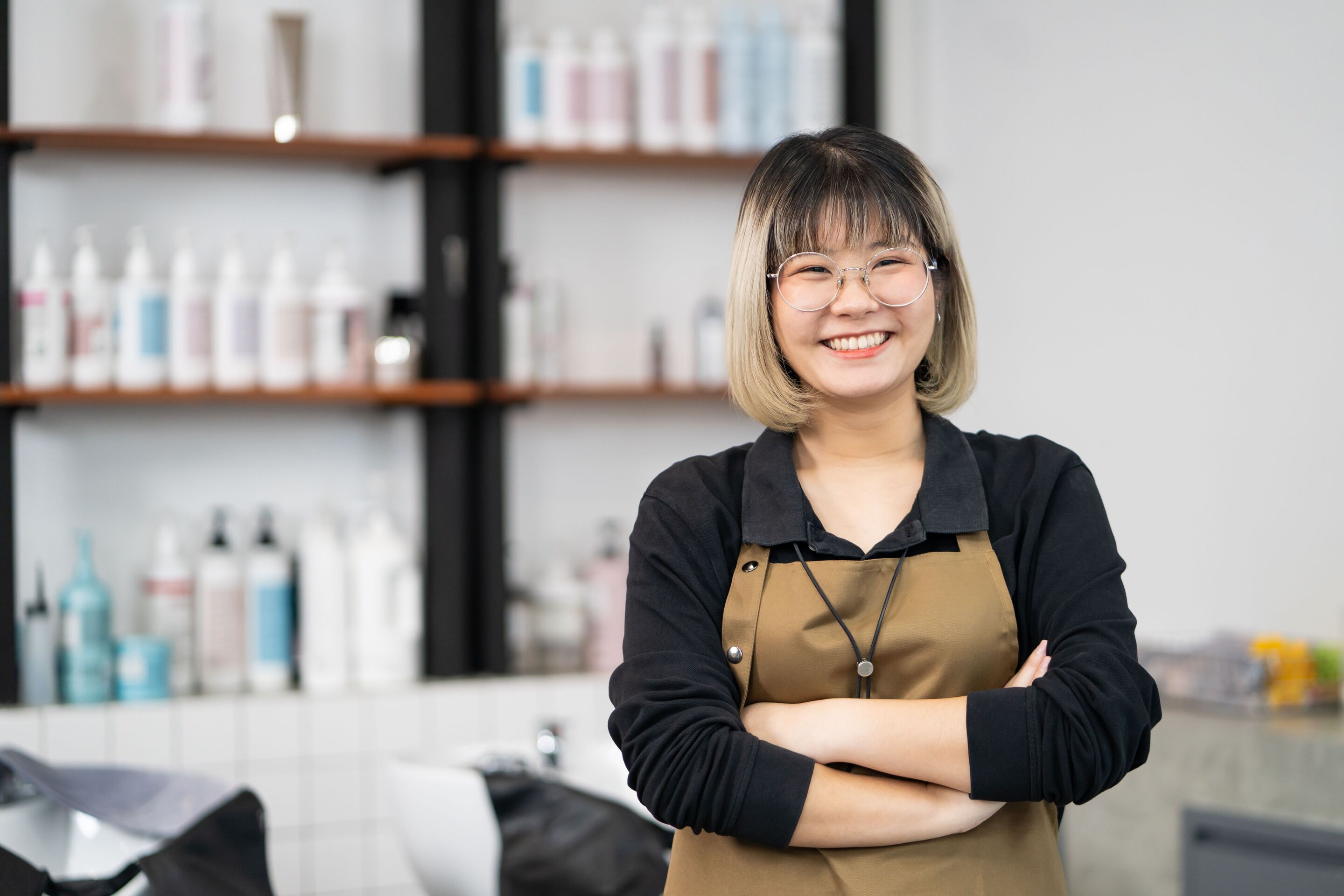 Asian hair stylist wearing an apron at a salon