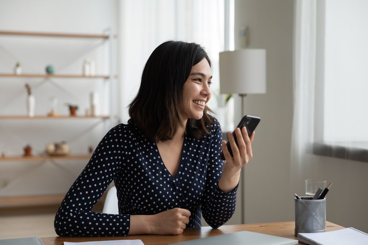 Asian woman holding up her phone and smiling