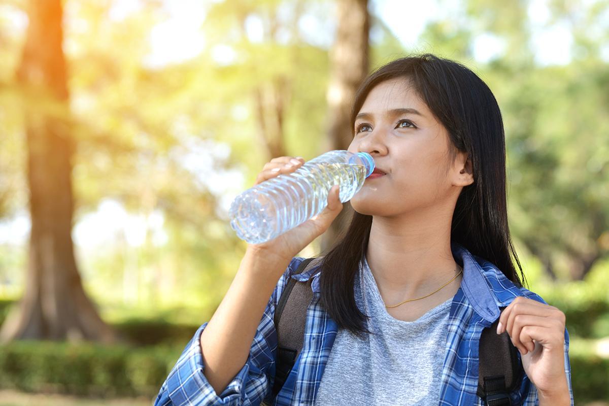 Asian woman drinking water outdoors