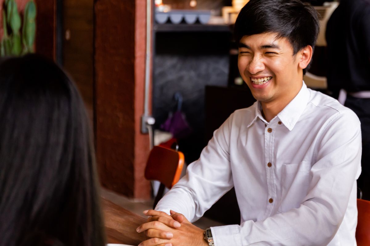 Shy Asian man smiling at a woman