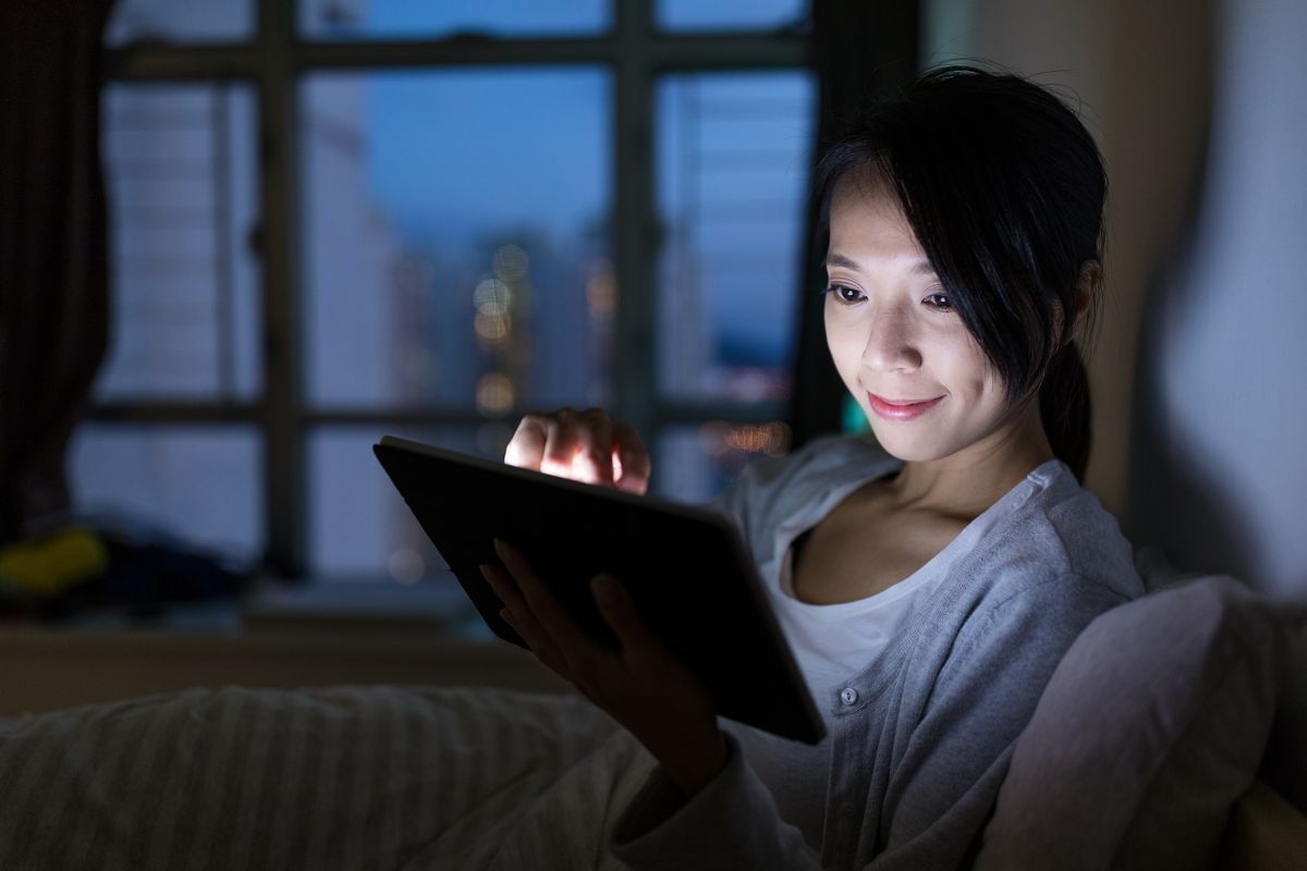Asian woman working on her tablet at night