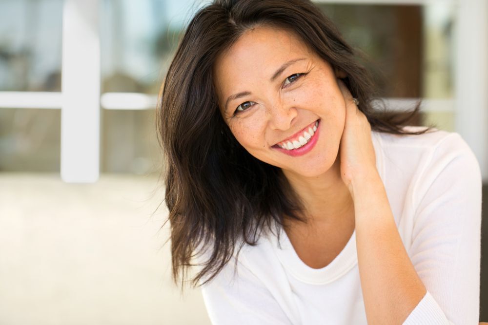 A middle aged Asian woman smiling.