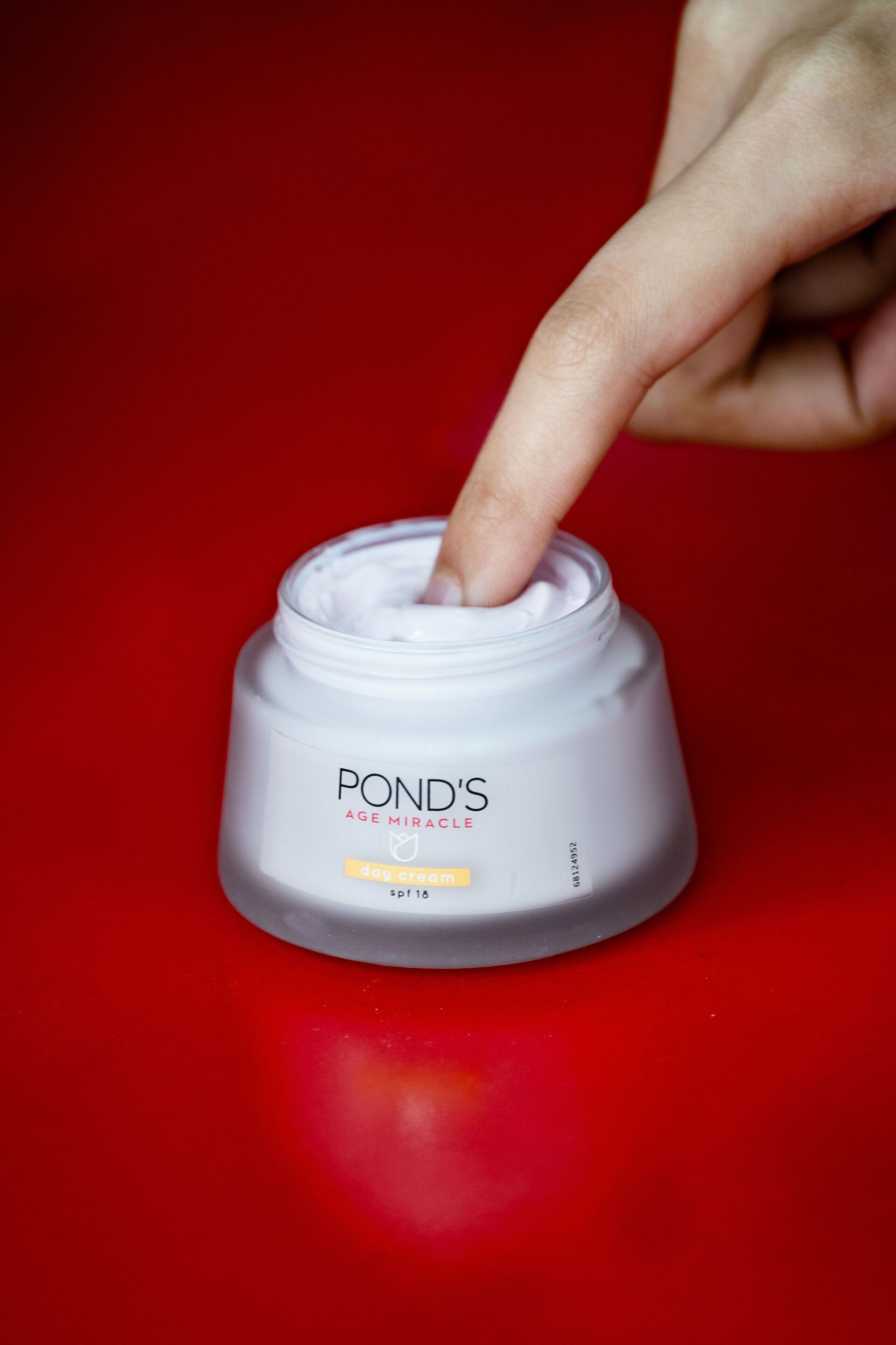 A finger dipping into the POND’S Age Miracle Day Cream