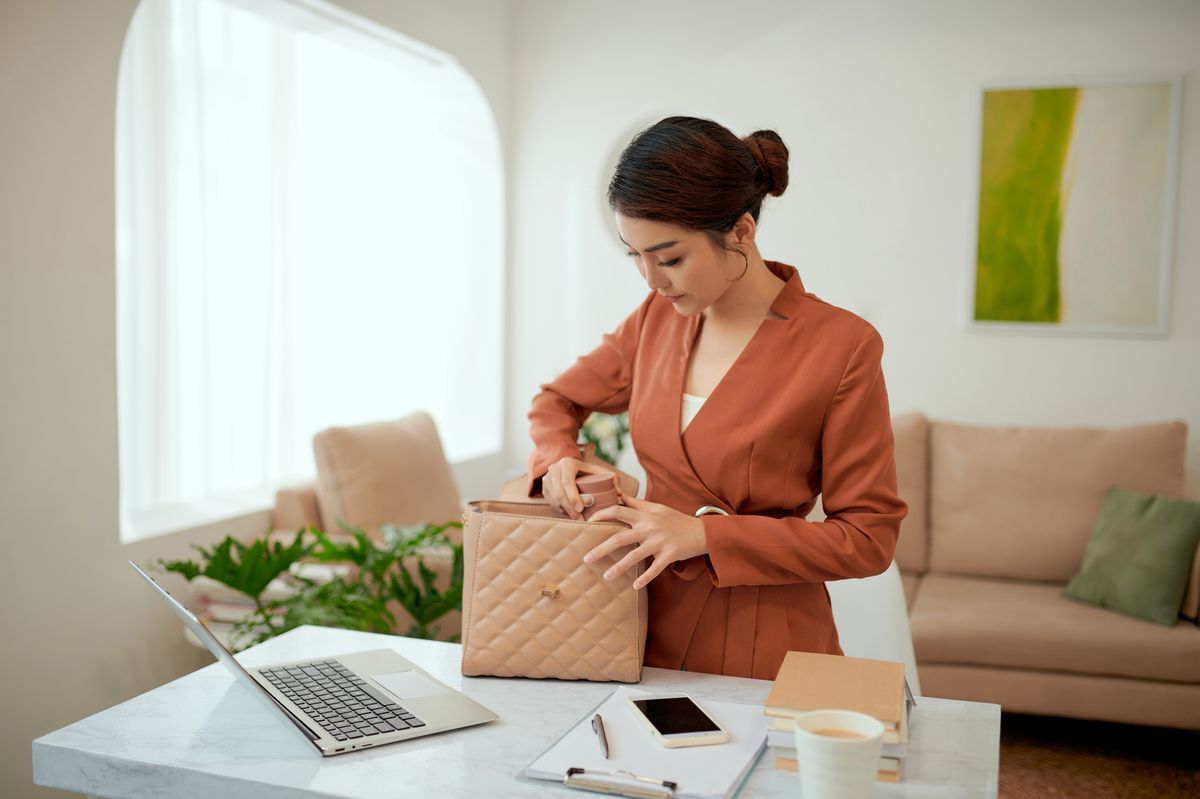 A woman holding an open handbag as she gets ready to leave for work. 