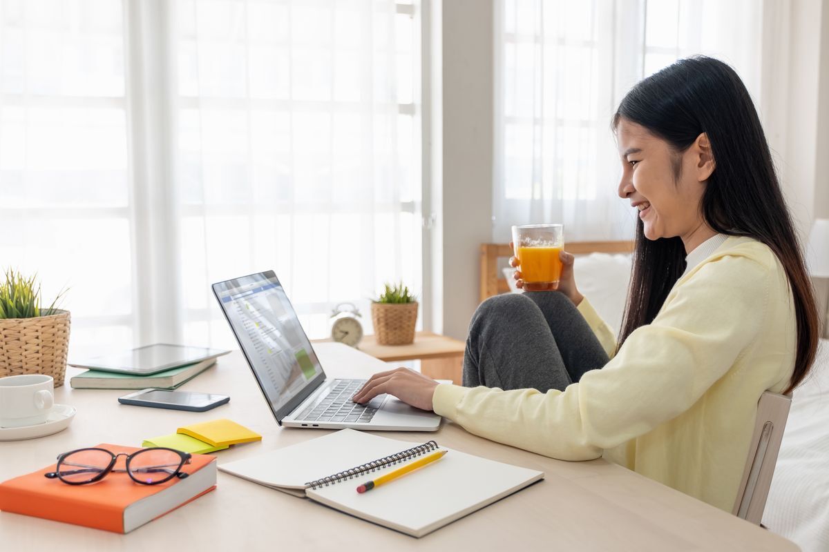 Asian woman drinking orange juice at work desk