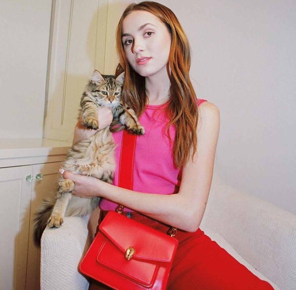 Woman in red and pink outfit holding a cat 