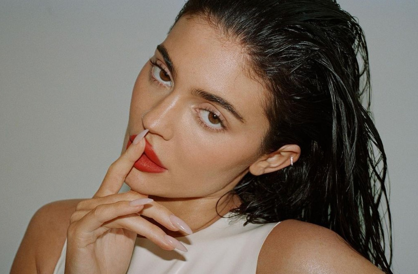 Closeup of Kylie Jenner posing in a white top.