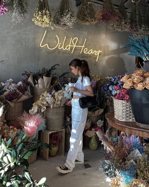 A woman wearing a white crop top and white ripped jeans.