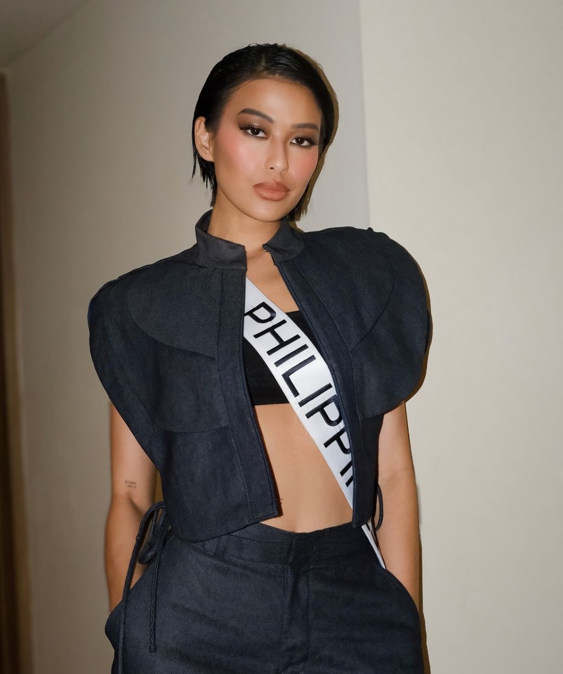 Michelle Dee wearing a Philippines sash and a black top and pants.