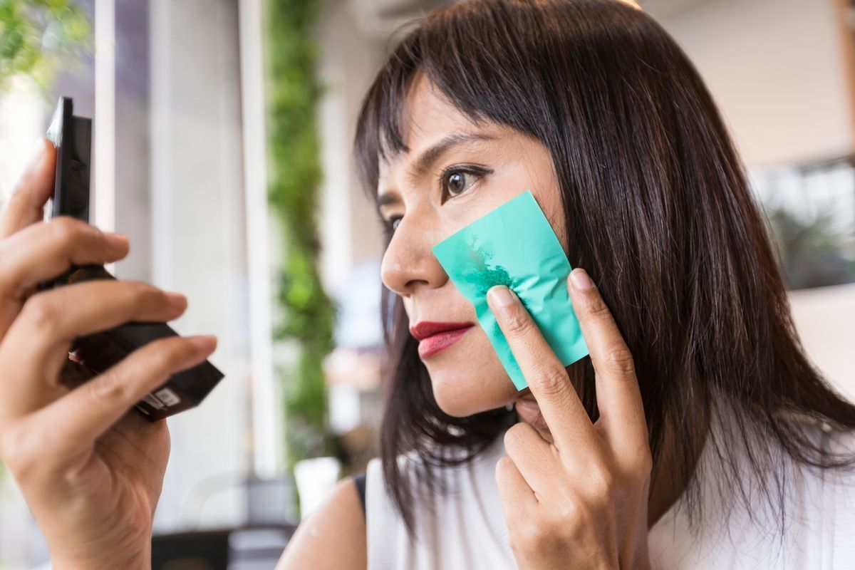 Asian girl is using an oil film to blot her face.