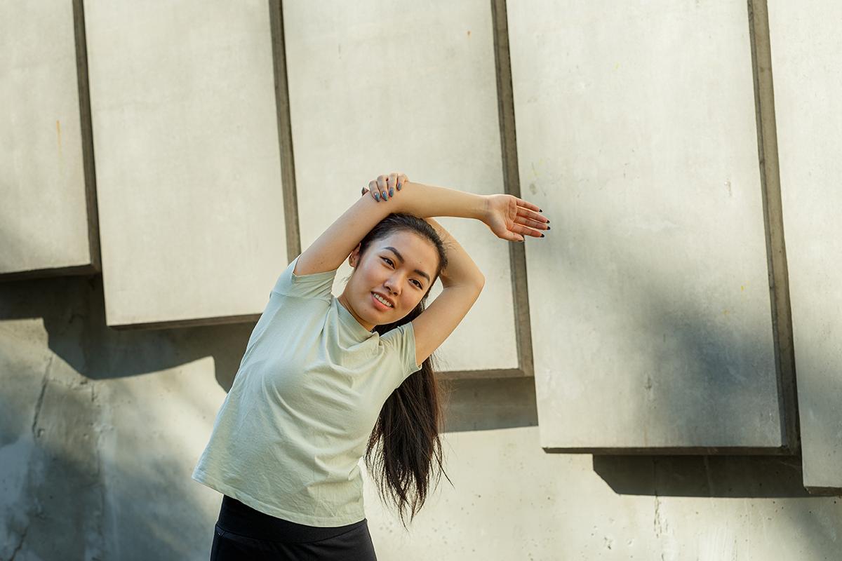 Asian woman in shirt stretching arms