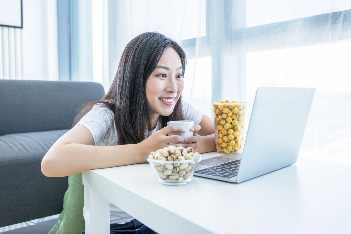 Filipino woman watching on her laptop with popcorn