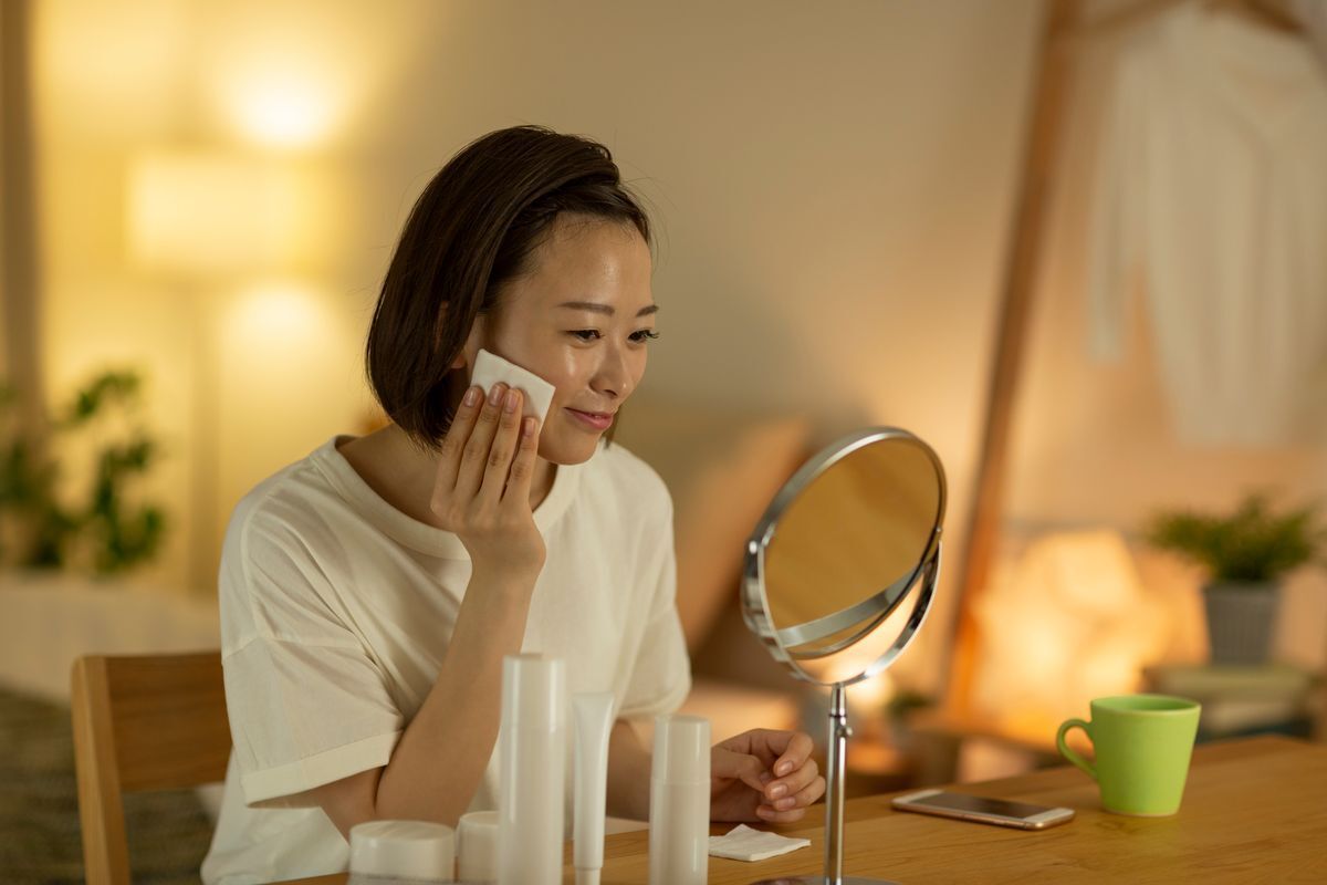 Asian woman with cotton pad in front of a mirror