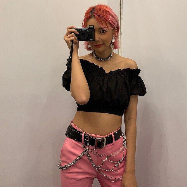 Asian woman with short pink hair.