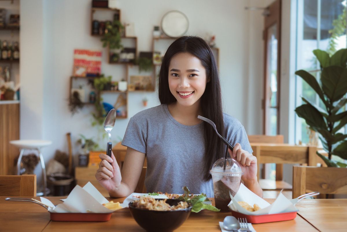 Asian woman with long hair having breakfast. 